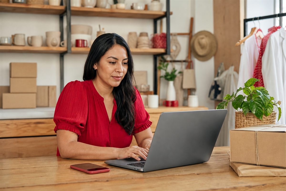 Duena de una tienda preparando pedidos mientras usa MiniTiendAI en su laptop